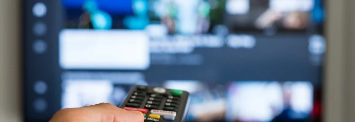 Hand bedient eine Fernsehfernbedienung.